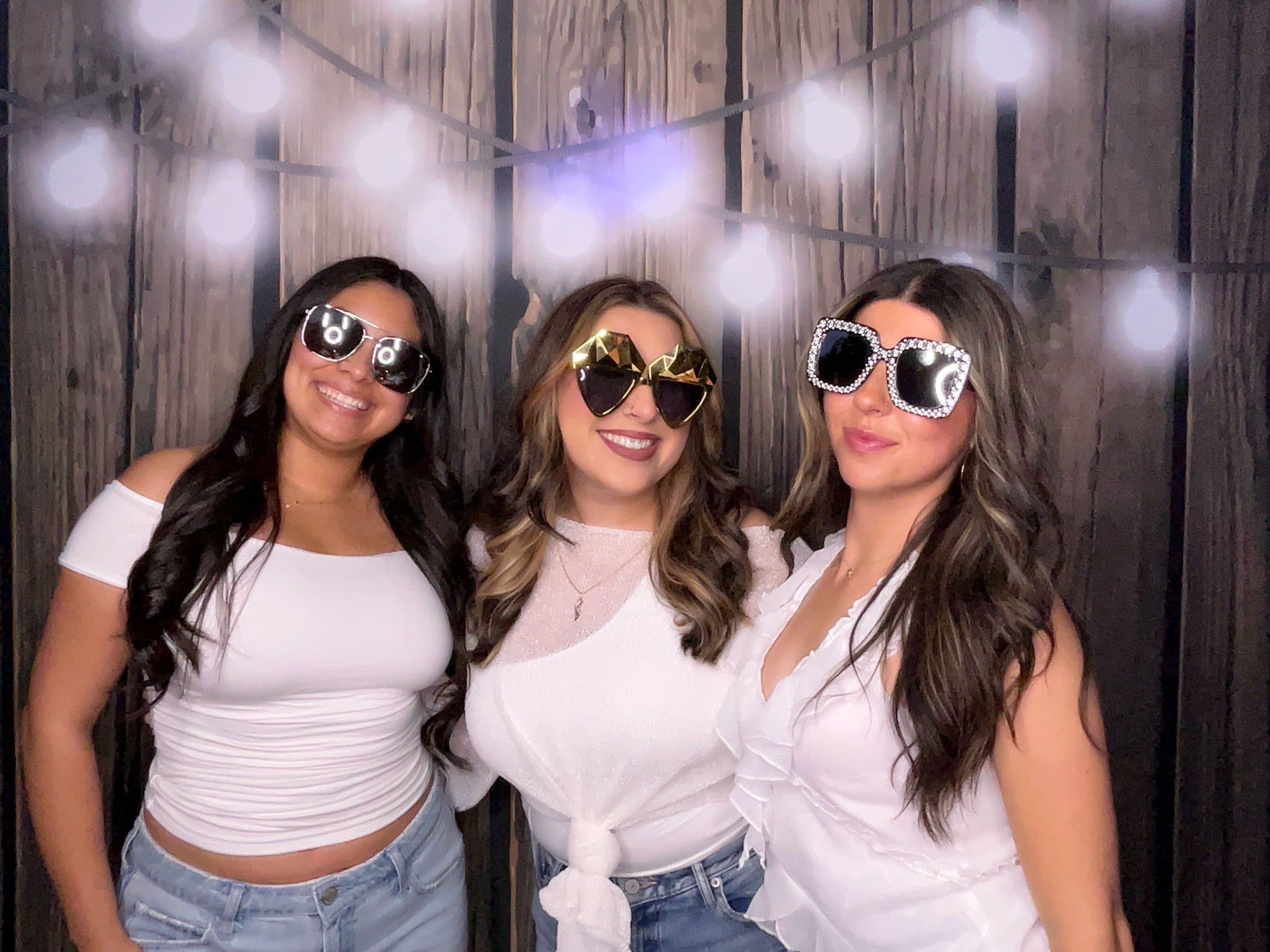 A group of guests with glasses in front of a country wood backdrop at a birthday event